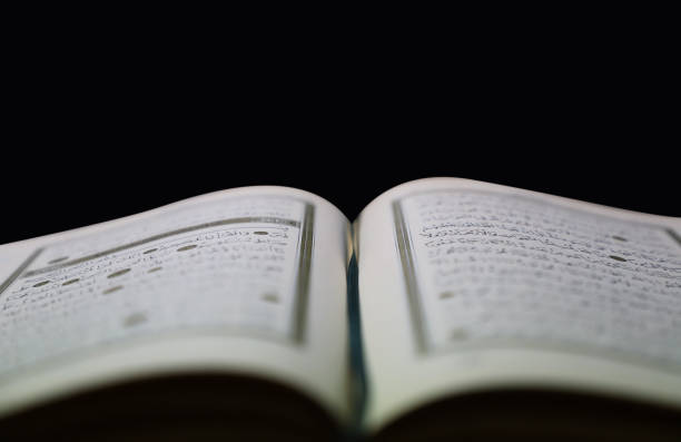 istock open quran pages with black background. surah yasin. include arabic letters. 1354752820