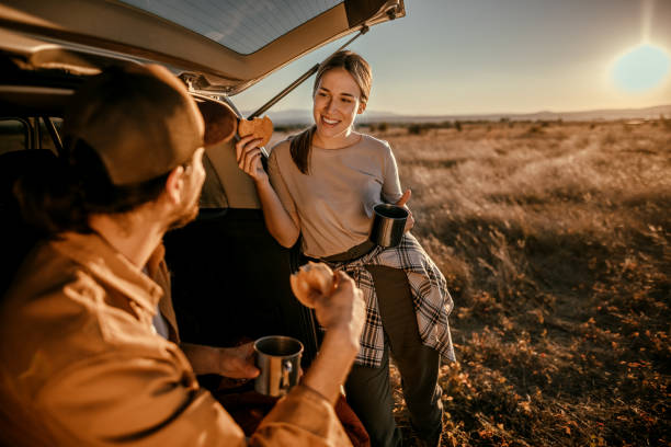 istock Happy couple having breakfast in car trunk on field 1354753129