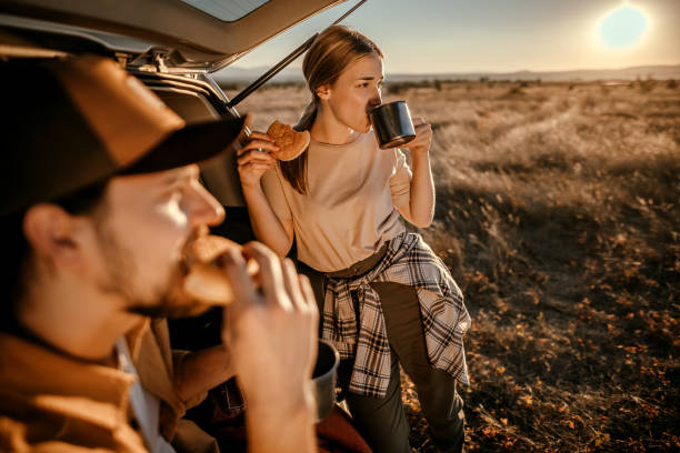 istock Happy couple having breakfast in car trunk on field 1354753159
