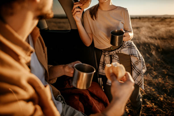 istock Happy couple having breakfast in car trunk on field 1354753192