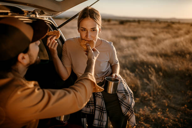 istock Happy couple having breakfast in car trunk on field 1354753215