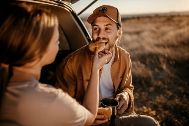 istock Happy couple having breakfast in car trunk on field 1354753251