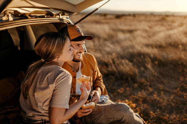 istock Happy couple having breakfast in car trunk on field 1354753804