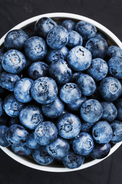 istock Blueberries in a white Cup on a black textured background. 1354754114