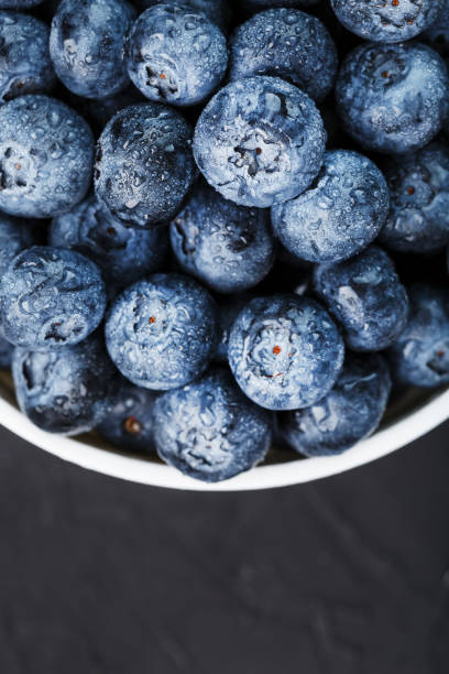 istock Blueberries in a white Cup on a black textured background. 1354754371