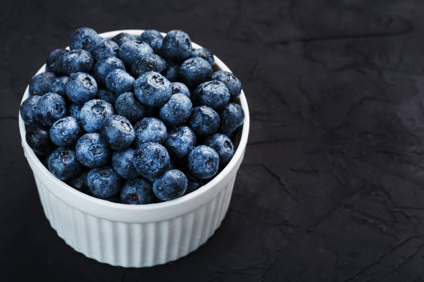 istock Blueberries in a white Cup on a black textured background. 1354754380