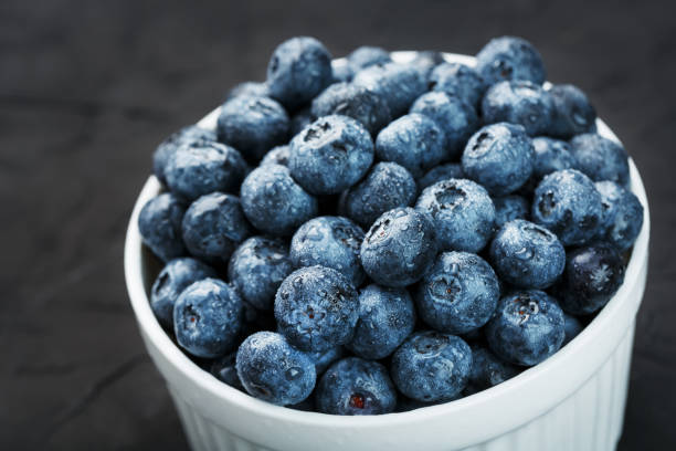istock Organic blueberries in a white Cup on a black Board. 1354754469