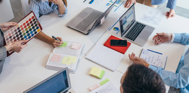 istock Colleagues collaborating and sharing ideas at desk in office. 1354759508