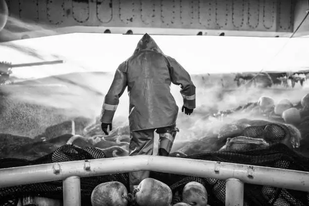 Photo of Fisherman on a trawler, over a fishing net