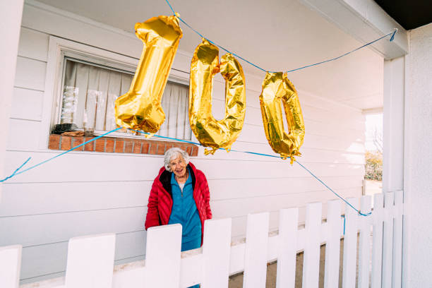 wide angle shot de uma idosa idosa caucasiana alegre celebrando seu 100º aniversário com balões dourados - number 110 - fotografias e filmes do acervo