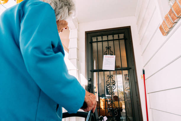 100-Year-Old Senior Woman Standing and Looking at an Eviction Notice on the Front Door of a Home