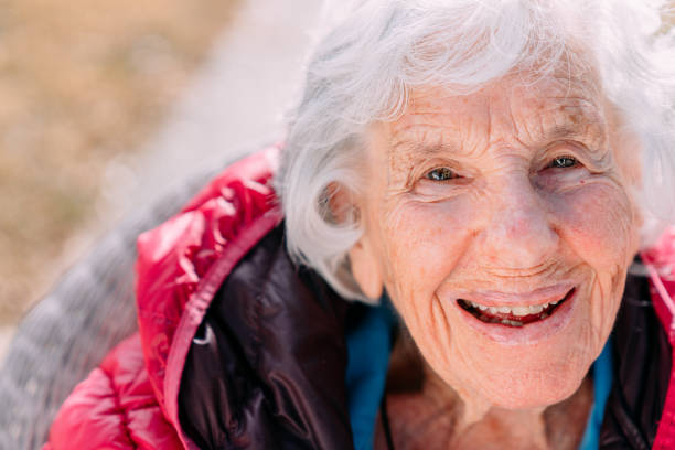 close-up shot of a cheerful 100-year-old elderly senior caucasian woman sitting outdoors in the winter - 110 imagens e fotografias de stock