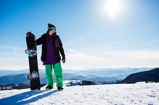 Male snowboarder with the ski googles on posing for a photo on a mountain