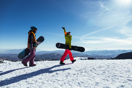 Two friends carrying their snowboards during a mountain ski trip