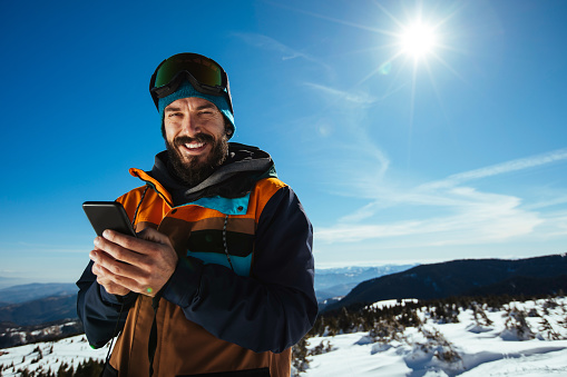 Smiling young man using his phone while on the mountain