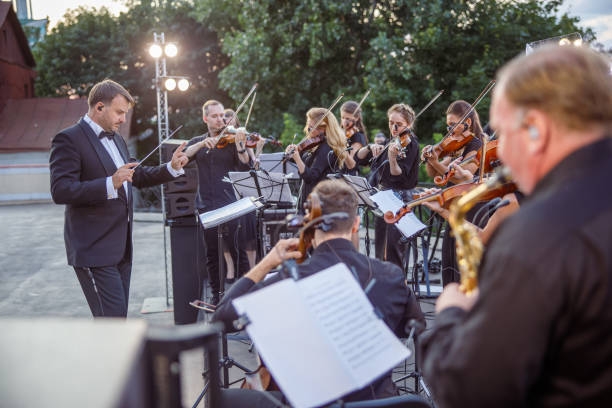 conductor directing orchestra performance on outdoor stage - band 40s imagens e fotografias de stock