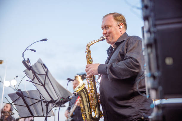 istock Male saxophonist playing in orchestra under blue sky 1354772463