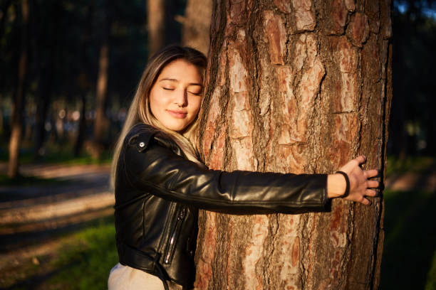 istock young woman reflects feeling hugging tree to protect forest in sunlight 1354773794
