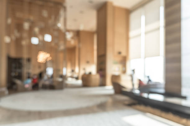 verschwommene hotel- oder bürogebäudelobby verwischt hintergrundinterne innenansicht in richtung empfangshalle, moderner luxusweißer raum mit verschwommenem flur und gebäudeglaswandfenster - defocused business office casual stock-fotos und bilder