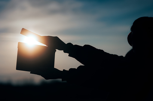 Silueta de manos sosteniendo una pizarra de película en la puesta de sol photo