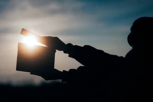 Photo of Silhouette of Hands Holding a Film Slate in the Sunset