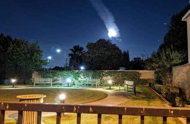 The Moon Above the Neighborhood A snapshot of the Full Moon, obscured by an airplane contrail, still shining brightly above a local dog park at night. contrail moon on a night sky stock pictures, royalty-free photos & images