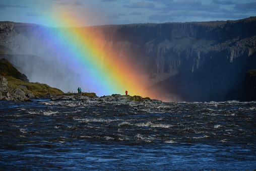 Tourists and a rainbow at the edge of Dettifoss waterfall, Jokulsargljufur canyon, Vatnajökull National Park, Iceland