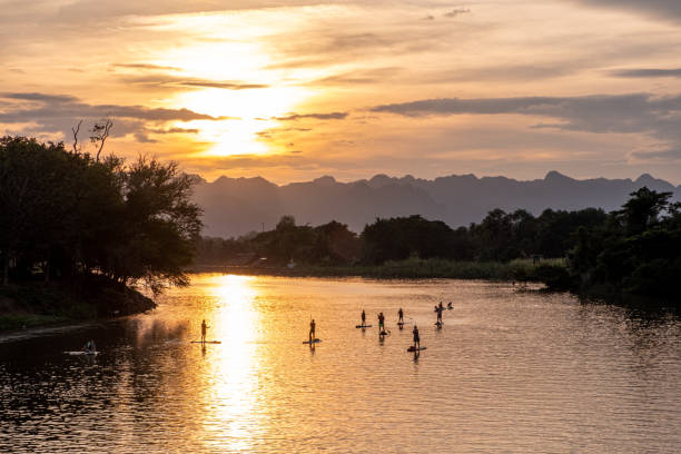 Paddleboarders at sunset on a jungle river stock photo