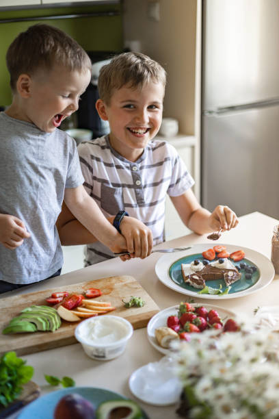 istock Two male little friends brother decorating morning sandwich with fruit, berries and chocolate paste 1354790708