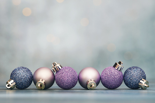Christmas background with glittery purple and blue Christmas ornaments and copy space for text