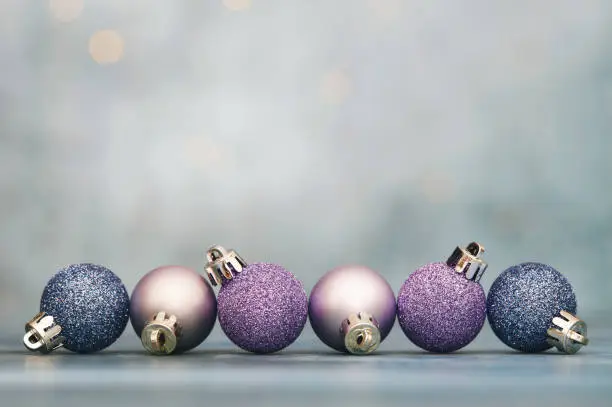 Photo of Christmas background with glittery purple and blue Christmas ornaments and copy space for text