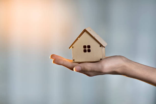 istock wooden small house in hand on a blue background, construction concept 1354803374