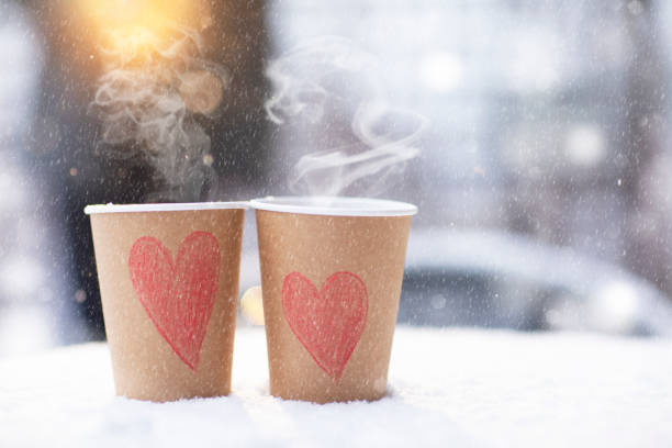 dos tazas artesanales de café con corazones parados en la nieve en un día de invierno, nieva el 14 de febrero - february fotografías e imágenes de stock