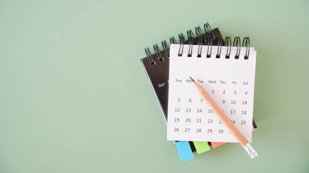 istock pencil on white and black calendar on green background for schedule, timeline, planning concept 1354804285