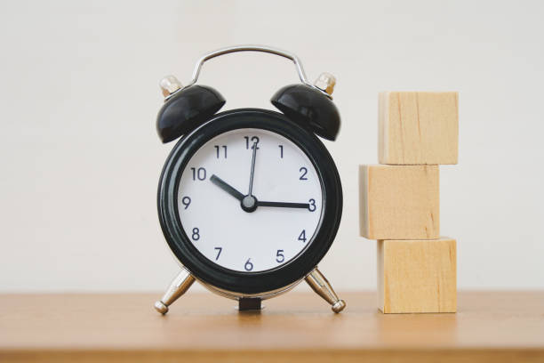 istock stack of blank square wooden block and black analog alarm clock on wood table for create and design   icon symbol to success, goal or target concept 1354804299
