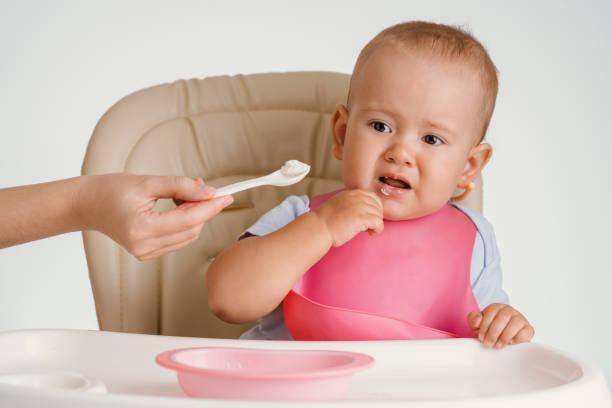 istock A baby in a pink bib refuses to eat with a spoon 1354804359
