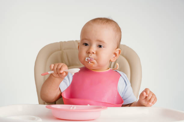 istock The child independently eats cottage cheese with a spoon while sitting on a chair on a white background 1354804362