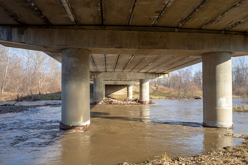 Concrete bridge over the river. Reinforced concrete block bridge structure, bottom view. Industrial landscape.