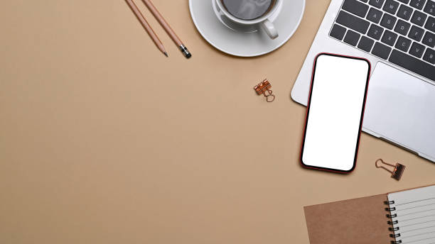 istock Flat lay modern workspace with smart phone, laptop computer and coffee cup on beige background. 1354805870
