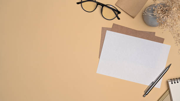 istock Top view blank paper card, sticky note and glasses on beige background. 1354805887