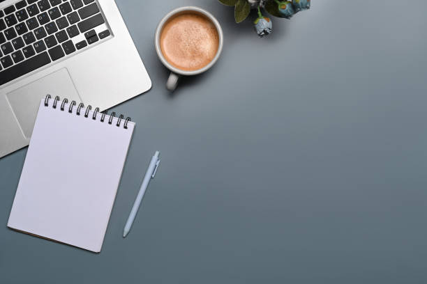 istock Top view laptop computer, empty notebook and cup of coffee on blue background. 1354805888