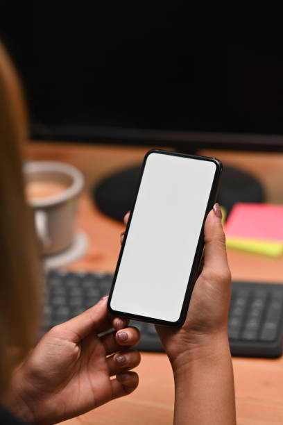 istock Over shoulder view of woman holding smart phone with empty display. 1354805896