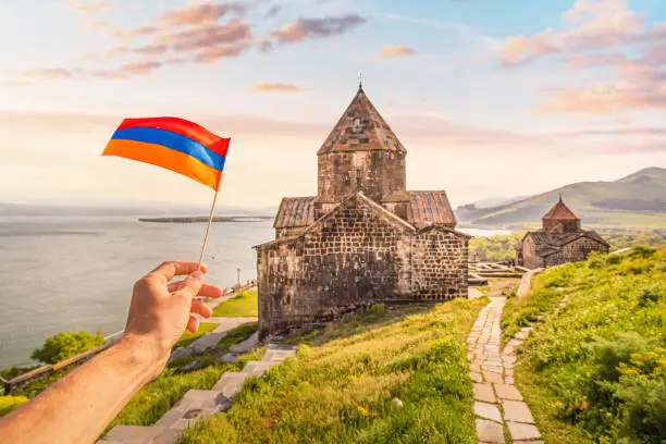 Photo of Armenian flag and famous Sevanavank Monastery on the shore of Lake Sevan. Travel landmarks and national patriotism concept