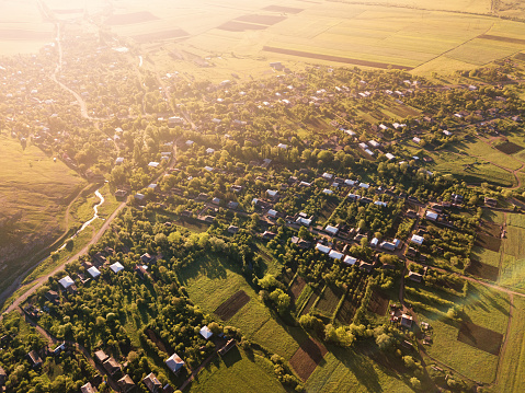Vista aérea panorámica de campos agrícolas verdes y arados y varias casas de pueblo iluminadas por el sol naciente photo
