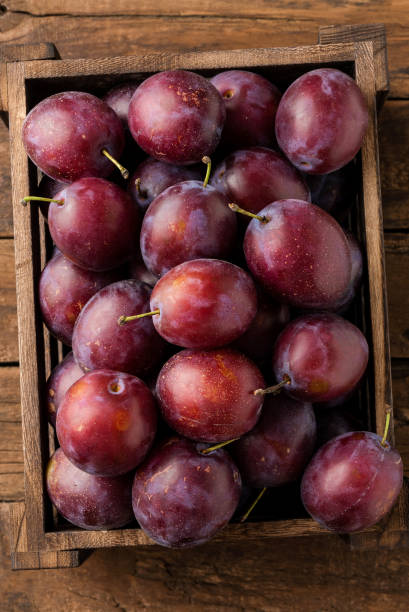 istock Fresh plums in crate on rustic wooden table. Top view. Close up 1354814287