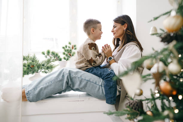 istock Happy mother with son sit on windowsill near Christmas tree 1354817080
