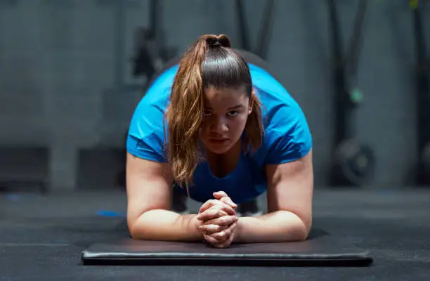 Photo of Shot of an attractive young woman holding a plank position while working out in the gym