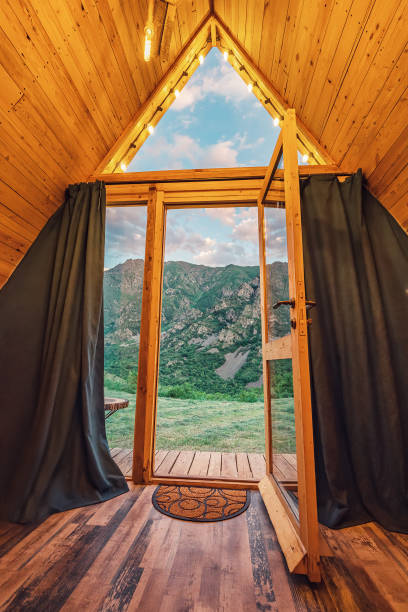 view from a small wooden chalet house in the mountains outside through a glass door and window. the concept of glamping and idyllic holidays - home interior cabin shack european alps imagens e fotografias de stock