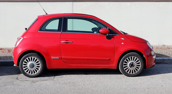 Udine, Italy. November 19, 2021. Red Fiat 500 with a small italian flag emblem on car body. Side view.