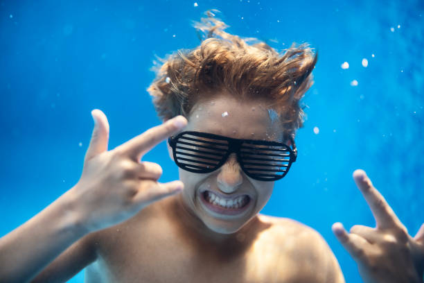 fajny rock and rollowy chłopiec w odcieniach migawki pod wodą - underwater mine zdjęcia i obrazy z banku zdjęć